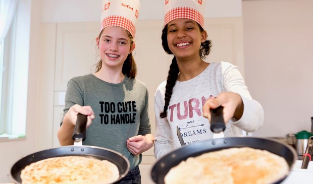 Leerlingen bakken pannenkoeken voor ouderen en genieten zo van een gezellig samenzijn.