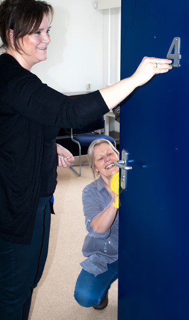 Wethouder Angelique Beekhuizen schroeft het kamernummer van een deur die ondertussen schoongemaakt wordt door Bernadette Pollen van Stichting MOL.