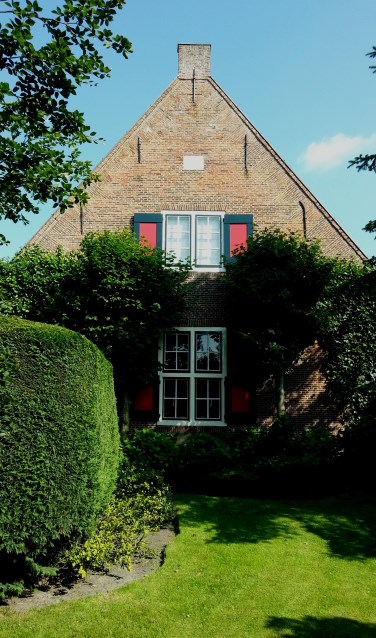 De kopgevel van de woning door het groen is bijna niet te zien.