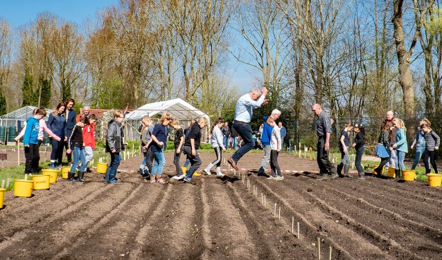 Wethouder Daan Binnendijk maakt een enthousiaste sprong terwijl hij de kinderen van de Leeuwerik voorgaat bij het paadjestrappen.