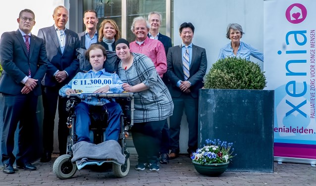 Martijn van Rees, ambassadeur van Xenia en nu zelf gast in het hospice, toont de cheque met achter hem Jacqueline Bouts. Verder v.l.n.r.: Lions Erik Donatz, Harry Horlings, Remco Fillipo, Theo Botden, John van der Hoeven en Paul Catsburg en twee vrijwilligers van Xenia: links Nasira en rechts Marijke.