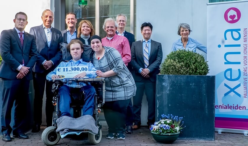 Martijn van Rees, ambassadeur van Xenia en nu zelf gast in het hospice, toont de cheque met achter hem Jacqueline Bouts. Verder v.l.n.r.: Lions Erik Donatz, Harry Horlings, Remco Fillipo, Theo Botden, John van der Hoeven en Paul Catsburg en twee vrijwilligers van Xenia: links Nasira en rechts Marijke.