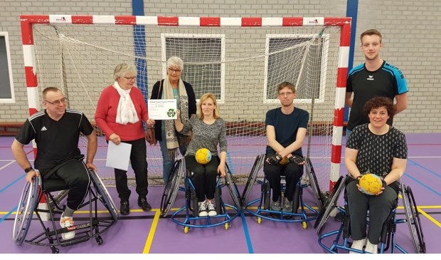Vrijwilligers van Herenstraat 63 overhandigen de cheque aan het handbalteam.