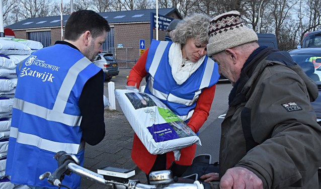 De wethouders Van Starkenburg en Salman deelden zakken compost uit. | Foto: Piet van Kampen