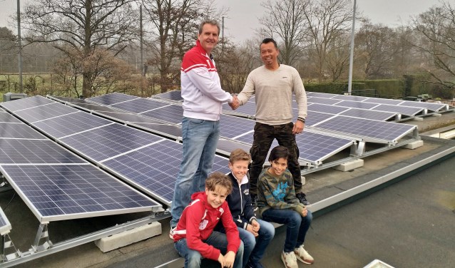 Erwin Gosenson van Solar Group draagt de zonnepaneleninstallatie over aan de voorzitter van OLTC Dick de Groot in het bijzijn van drie jeugdleden.