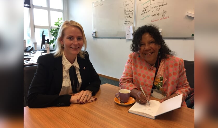 Wethouder Van der Laan neemt het boek van Helen Workala in ontvangst.