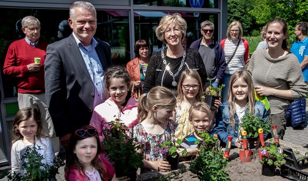 Wethouder Daan Binnendijk, burgemeester Laila Driessen en MEC medewerkster Marieke Weishaupt met een aantal jonge natuurliefhebbers bij de plantenbak, waarin vlak voor de opening de laatste plantjes gezet werden.
