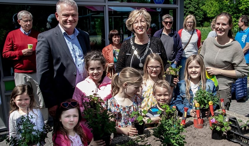 Wethouder Daan Binnendijk, burgemeester Laila Driessen en MEC medewerkster Marieke Weishaupt met een aantal jonge natuurliefhebbers bij de plantenbak, waarin vlak voor de opening de laatste plantjes gezet werden.