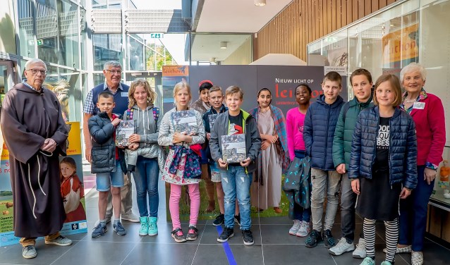 Rechts museumdirecteur Bob Reidsma, voor de gelegenheid verkleed als middeleeuwse monnik, met twee museummedewerkers en kinderen van de Leiderdorpse basisscholen die de boeken kwamen afhalen.