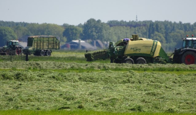 De maaimachines hebben hun werk gedaan in de Achthovenerpolder. Tractoren zuigen het gemaaide gras naar binnen en persen het tot blokken.