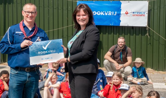 Wethouder Angelique Beekhuizen overhandigt het bord ‘Rookvrij’ aan voorzitter Bas van den Berg van de scoutingvereniging.