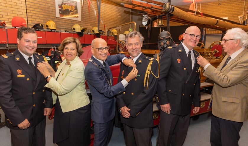 Burgemeester Emile Jaensch en oud-burgemeesters Els Timmers-Van Klink en Sjoerd Scheenstra speldden de draagspeldjes op bij de brandweerlieden.