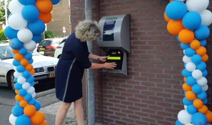 Wethouder Corien van Starkenburg hangt een AED op aan het gemeentehuis