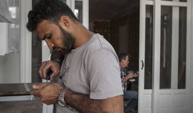 Hasan Alkasas uit Syrie en aannemer op de achtergrond Peter de Groot aan het werk in de Drie Mollen. Foto: Michel van den Langenberg