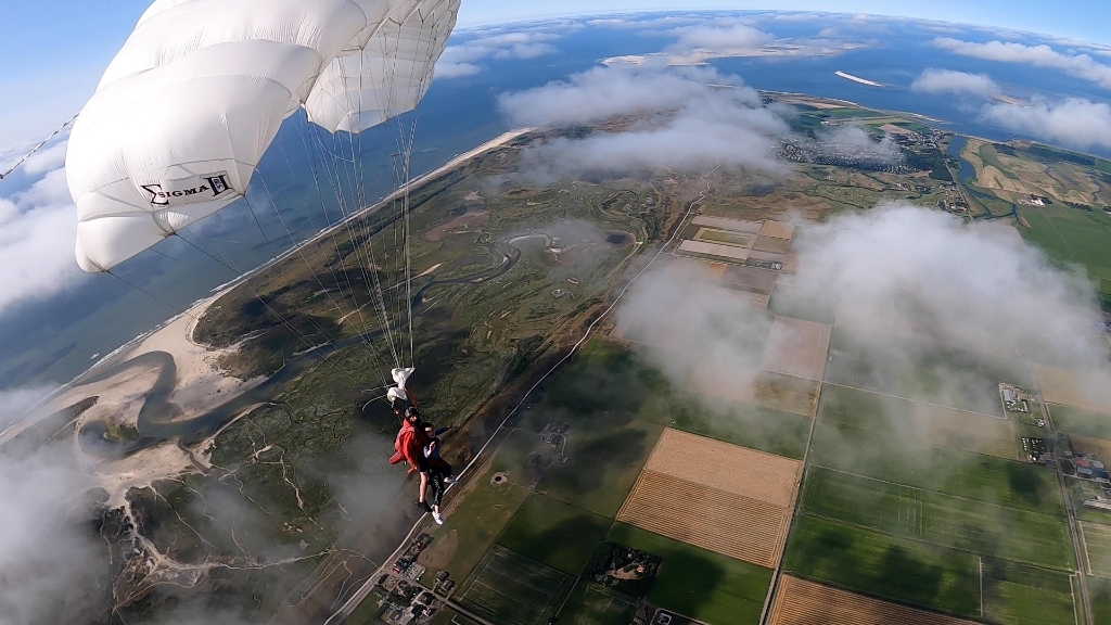 Tandem- instructeur en passagier vliegen onder de parachute ter hoogte van De Slufter