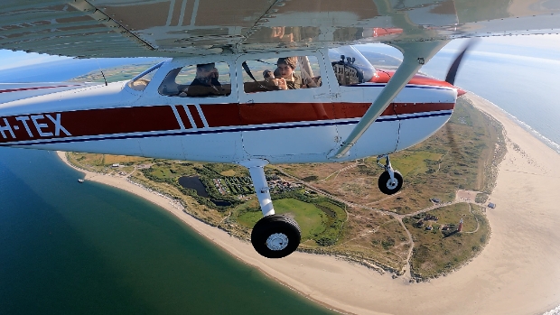 Rondvlucht toestel vliegt tussen vuurtoren van Texel en de Vliehors