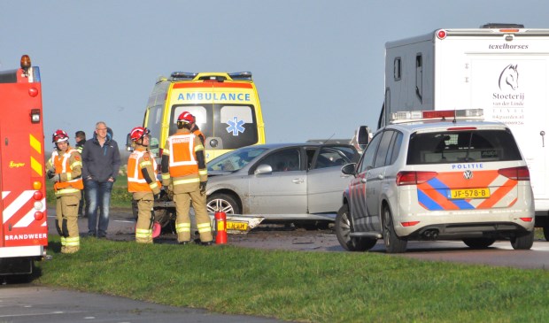 Hulpverleners bij de beschadigde auto.