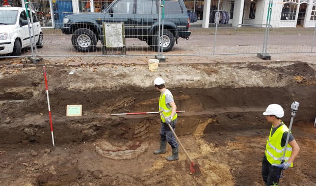 Een medewerker van Arceologie West-Friesland kijkt naar de restanten van de plaggenput.
