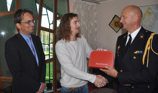 Wouter Krab krijgt de geboortekoffer van de brandweer uit handen van brandweercommandant Jelle de Boer en burgemeester Michiel Uitdehaag.
