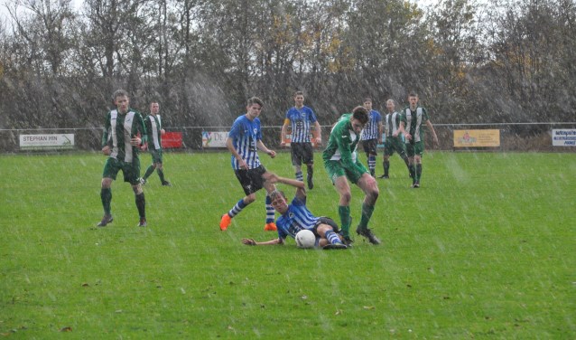 Terwijl de regen met bakken uit de hemel valt, vechten ZDH-speler Barry van der El (links) en Marijn Bakker van Oosterend een verbeten duel uit. (Foto: Willem Sangers)