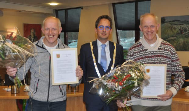 Jos (links) en Paul (rechts) met de gemeentelijke oorkonde die ze van burgemeester Michiel Uitdehaag kregen.