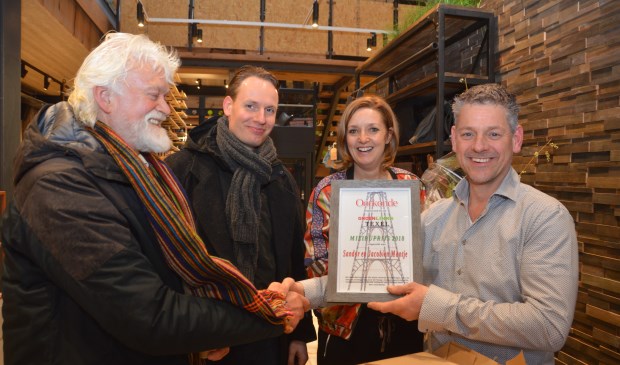 Jaap Vlaming en Sander van Knippenberg overhandigen de Groen Links Milieuprijs aan Sandor en Jacobine Mantje bij de opening van hun nieuwe winkel in De Koog.