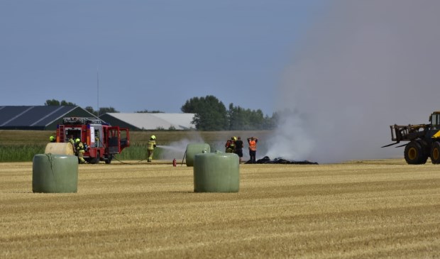 De brandweer blust de brandende hooibalen.