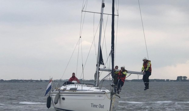 Een paar man van de KNRM in de giek van de Time Out om het schip los te krijgen van de Bollen.