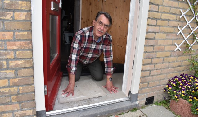Wim de Graaf toont de vochtplek onder het vloerkleed achter de voordeur.