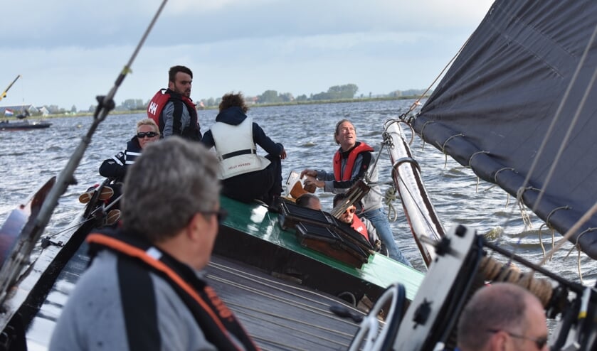 Schipper Kees van der Kooij (midden achter aan het helmhout) kijkt omhoog naar wimpel en zeil.