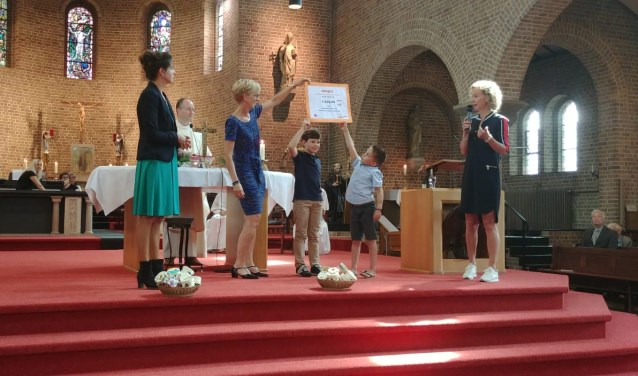 Twee communicanten overhandigen de cheque