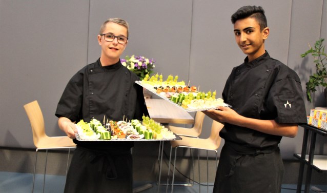 Rowdy (links) en Hani serveren trots de hapjes die ze gemaakt hebben op de eerste burenavond. (Foto: M. Kleinpenning)