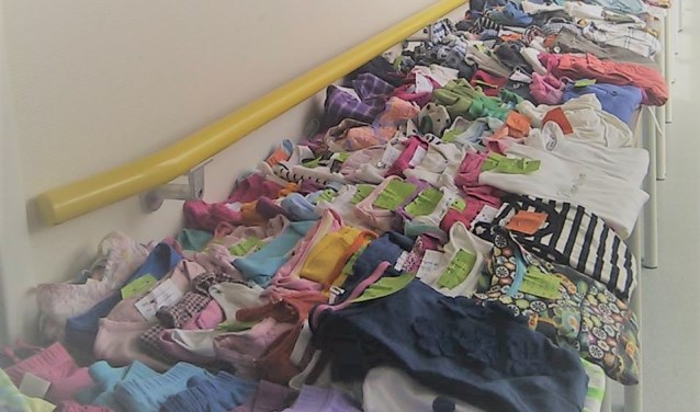Kleding ligt in lange rijen op maat uitgestald op de kinderkledingbeurs. (foto: Margré Mollink)