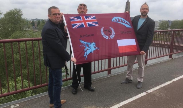 Karl van den Top en Kevin van Guilik overhandigen het eerste exemplaar van de Herdenkingsvlag aan Marcel Legerstee. (foto: Ome Joop's Tour)