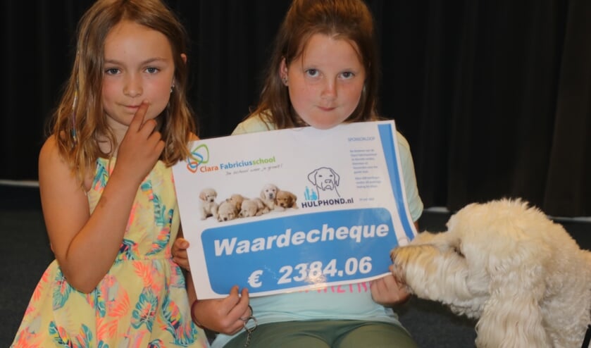Marieke en Wendy overhandigen de waardecheque aan Nora, hulphond van Mirjam, ambassadeur van Stichting Hulphond. (foto: Moss Tijssens)