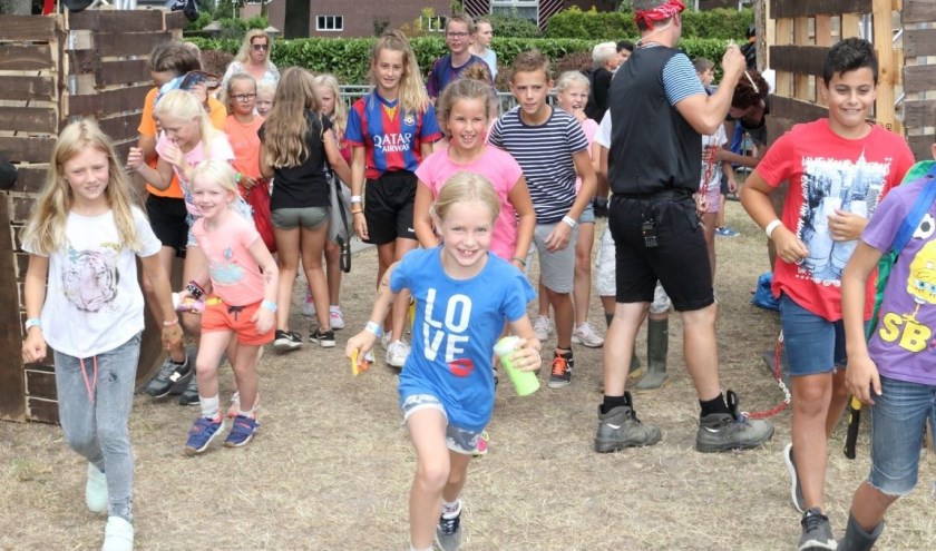 Kinderen rennen door de poort het terrein van Kinderdorp Angeren op.